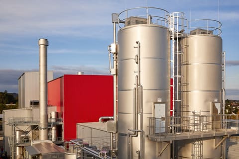 Cuves inox et bâtiment rouge d'un site de production
