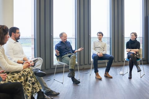 Réunion informelle de collaborateurs devant de grandes baies vitrées